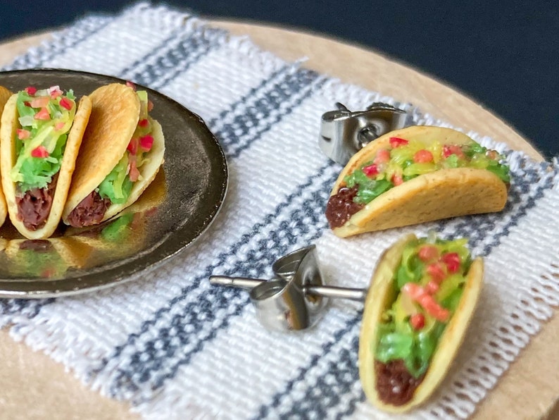 Peut inclure: Une paire de boucles d'oreilles &agrave; clous argent&eacute;es avec des tacos miniatures. Les tacos sont faits en p&acirc;te polym&egrave;re et pr&eacute;sentent une garniture brune, de la laitue verte et des garnitures rouges et jaunes.