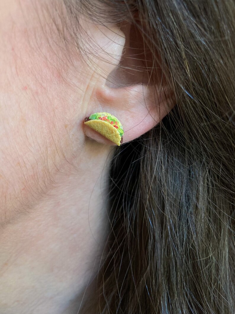 Peut inclure: Une paire de petites boucles d'oreilles en forme de taco r&eacute;alistes. Les boucles d'oreilles sont en p&acirc;te polym&egrave;re et peintes pour ressembler &agrave; un taco avec de la laitue, de la tomate et du fromage.