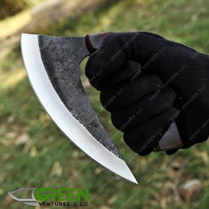 May include: A curved, silver-coloured knife with a wooden handle. The knife is held in a gloved hand.