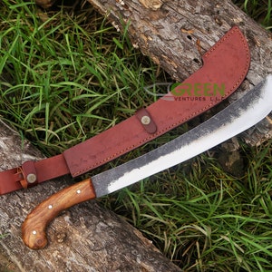 May include: A brown leather sheath with a silver buckle and the text "GREEN VENTURES LLC" is attached to a long, curved, silver blade with a wooden handle. The blade has a dark, aged finish.