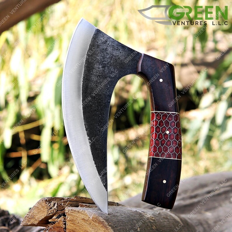 May include: A curved, black, steel axe with a wooden handle. The handle has a red and white honeycomb pattern. The axe is resting on a piece of wood.