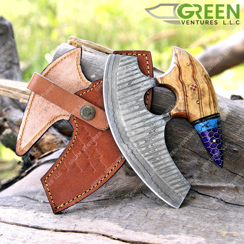 May include: A Damascus steel cleaver with a wooden handle and a leather sheath. The handle has a blue and purple inlay. The cleaver is a kitchen tool used for chopping and slicing.