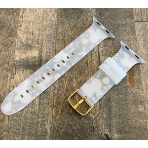 May include: A white silicone Apple Watch band with a floral pattern and a gold buckle.