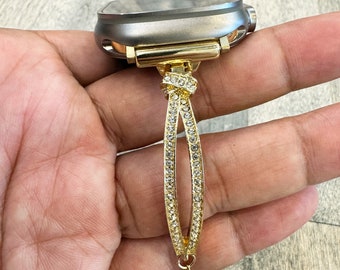 May include: A gold watch band with a crystal design. The band is attached to a gray watch face.