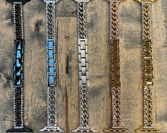 May include: Five different Apple Watch bands with a chain link design and crystal accents. The bands are in black, silver, blue, gold, and rose gold.