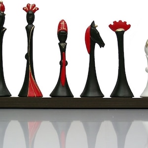 Pu&ograve; includere: Un set di sette pezzi degli scacchi, ognuno con un design unico. I pezzi sono in ceramica e sono dipinti in nero, bianco e rosso. I pezzi sono disposti in fila su una superficie marrone scuro.