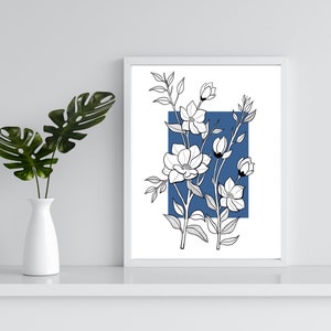 May include: A white framed print with a black and white line drawing of flowers on a blue background.