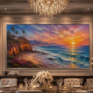 Op de afbeelding: Een groot rechthoekig olieverfschilderij met een zonsondergang aan de kust, een rotsachtige klif, palmbomen en oceaangolven in oranje, roze en blauwe tinten. Het kunstwerk hangt in een formele eetkamer boven een lange tafel met stoelen.