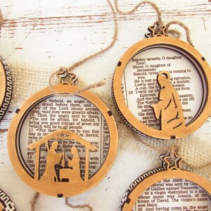 May include: Wooden Christmas ornaments with a circular design, featuring cut-out silhouettes of religious figures and scenes. Each ornament has a star-shaped top and is strung with twine. The background includes text from a book.