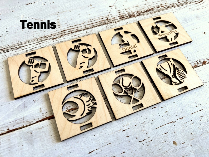 May include: Set of seven wooden coasters with a tennis theme. Each coaster features a different tennis-related design, including a tennis player, a tennis racket, and a tennis ball. The coasters are personalized with the names "Samantha" and "Daniel".