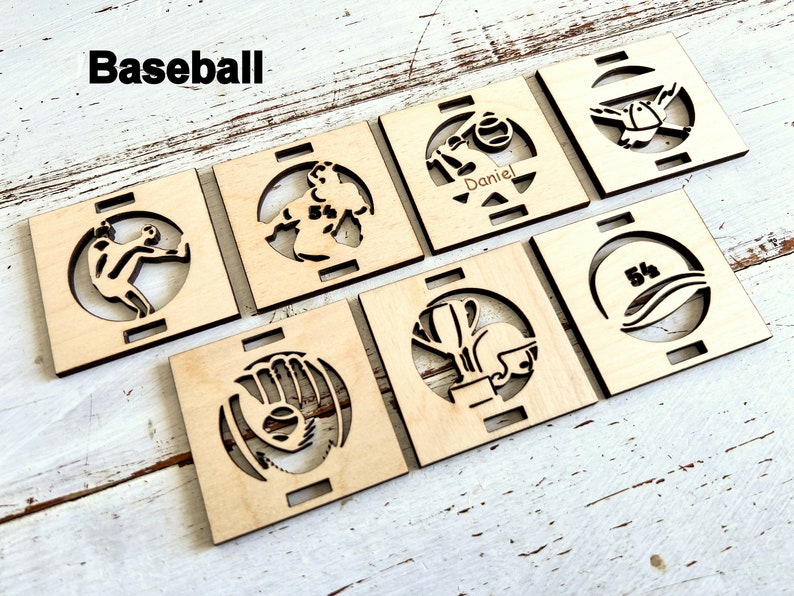 May include: Set of six wooden baseball-themed coasters with various designs, including a baseball glove, a baseball player, a baseball cap, and a baseball bat. The coasters are made of natural wood and have a light brown color.