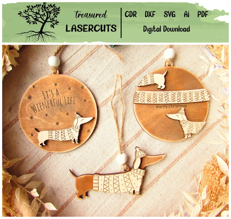 May include: Wooden dachshund ornaments with etched details. One ornament reads "It's a Wienerful Life" and another says "merry christmas". The dachshunds are wearing sweaters and hats. The ornaments are hanging from twine.