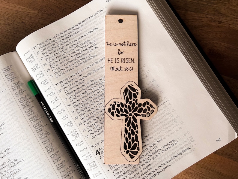 May include: A wooden bookmark with a cross design and the text "He is not here for HE IS RISEN. (Matt. 28:6)"