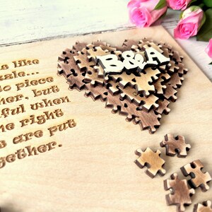 May include: A wooden heart-shaped puzzle with the letters "B&A" on top. The puzzle is on a light wood background with the text "Love is like a puzzle... hard to piece together, but beautiful when all the right pieces are put together."