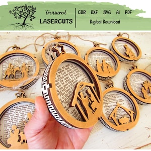 May include: Circular wooden Christmas ornaments featuring laser-cut Nativity scenes and text from the Bible. The ornaments have a brown frame with a white and brown patterned edge. The text "Treasured Lasercuts" is at the top.