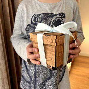 May include: A wooden box with a light blue ribbon tied around it. The box has a star and candy cane design engraved on it.