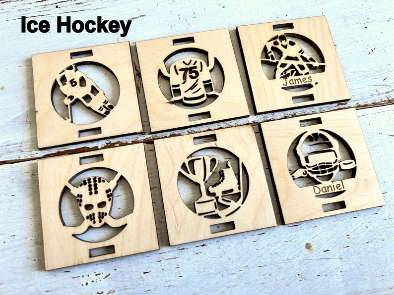 May include: Six wooden squares with laser cut designs of hockey equipment and the names "James" and "Daniel".