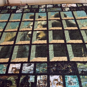 May include: A large patchwork quilt featuring a central image of a brown bear face framed by a grid of tan and dark green fabric strips. The border consists of smaller square panels depicting various wildlife scenes including wolves and bears.