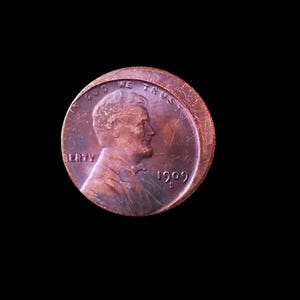 May include: A copper-colored 1909 US penny with the words "In God We Trust" and "Liberty" visible. The profile of Abraham Lincoln is on the coin.