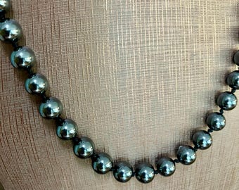 May include: A black beaded necklace with large, round, shiny beads.