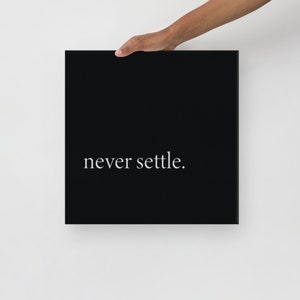 Può includere: Stampa su tela nera con testo bianco che recita "never settle."