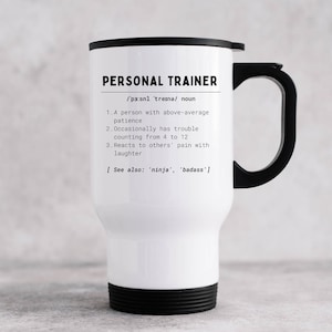 May include: White travel mug with a black lid and handle. The mug has a black and white design with the text "PERSONAL TRAINER /pa:snl 'tresna/ noun 1.A person with above-average patience 2. Occasionally has trouble counting from 4 to 12 3. Reacts to others' pain with laughter [See also: 'ninja', 'badass']"