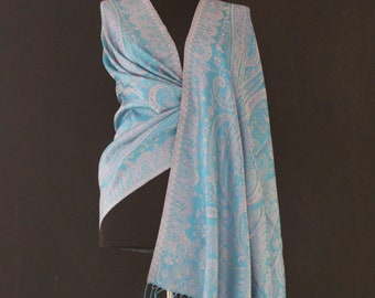May include: A light blue paisley patterned scarf with a white background and fringe trim.