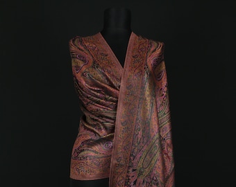 May include: A pink and black paisley patterned shawl with fringed edges draped over a black mannequin.