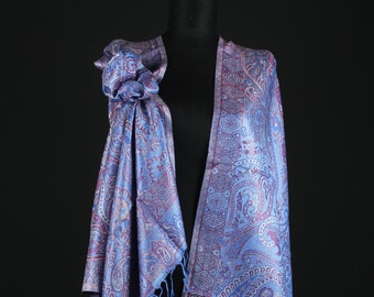 May include: A blue and purple paisley patterned shawl with fringed edges. The shawl is draped over a mannequin.