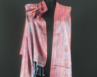May include: A pink and blue paisley patterned scarf with fringed edges. The scarf is draped over a mannequin.