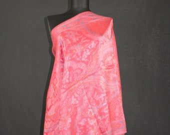 May include: A pink paisley patterned shawl with a fringed edge. The shawl is draped over a mannequin.