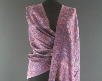 May include: A purple and blue patterned shawl with a fringed edge. The shawl is draped over a mannequin.