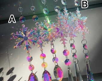 Pode incluir: Cinco ornamentos de floco de neve de cristal iridescente com prismas de cristal pendurados. Os flocos de neve estão suspensos em cordas transparentes e os prismas são de várias formas e tamanhos.