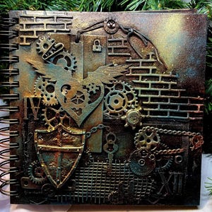 May include: A steampunk-themed journal with a spiral binding. The cover features a textured design with gears, a shield, a heart with wings, and brickwork in shades of bronze, teal, and brown. The journal has a metallic finish.