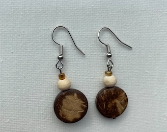 May include: A pair of brown wooden earrings with a white bead and a silver hook.