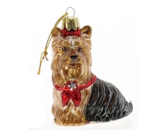Può includere: Un ornamento natalizio in vetro a forma di cane Yorkshire Terrier. Il cane ha pelo marrone e nero, un fiocco rosso sulla testa e un collare rosso con un fiocco. Un anello dorato è attaccato per appenderlo.
