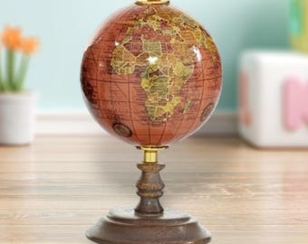 May include: A decorative globe with a reddish-brown finish, featuring gold-colored continents and a detailed map. The globe sits on a dark wooden stand with a brass-colored metal accent. The globe is a classic home decor item.