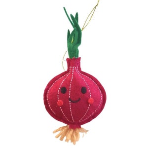 Puede incluir: Adorno navideño con forma de cebolla roja sonriente, con brotes verdes y raíces marrones. El adorno de fieltro tiene costuras blancas y una cuerda dorada para colgar.