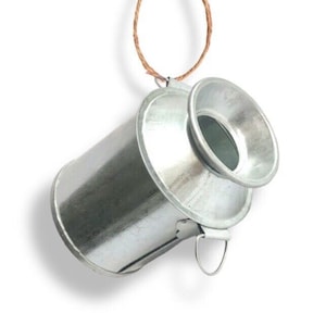 May include: A small, silver metal milk can with a handle and a spout. The can is hanging from a brown twine string.