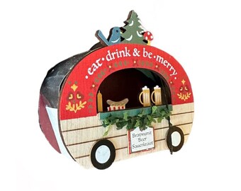 May include: A wooden Christmas ornament shaped like a red and white food cart with the text "eat. drink & be. merry." The cart has a window with a hot dog, mustard, and two mugs of beer. The cart has a sign that reads "Bratwurst Beer Sauerkraut".