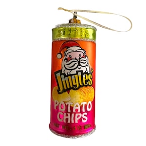 May include: A red and orange Christmas ornament shaped like a can of potato chips. The can has a Santa Claus illustration and the text "Jingles Potato Chips" on it. The ornament has a gold string for hanging.