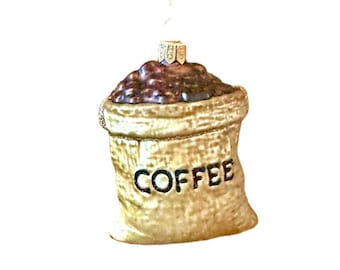 Może przedstawiać: Szklana ozdoba choinkowa w kształcie worka jutowego wypełnionego ziarnami kawy. Worek ma nadrukowane słowo "COFFEE".