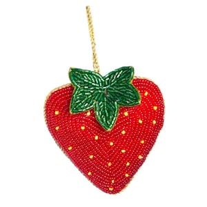 May include: A red and green beaded strawberry ornament with a gold string for hanging.