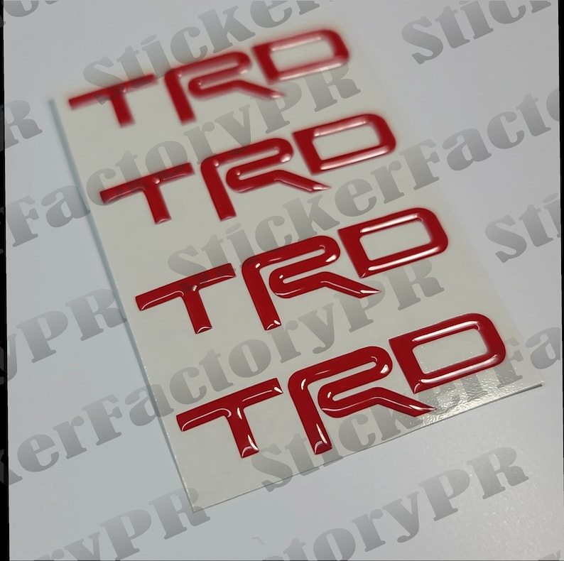 May include: Four red 3D "TRD" stickers on a white background. The stickers are glossy and have a raised design.