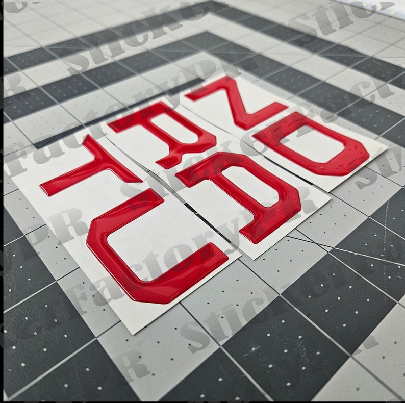 May include: Four red, 3D plastic numbers, 1, 2, 0, and 0, on a white background. The numbers are raised and have a glossy finish.