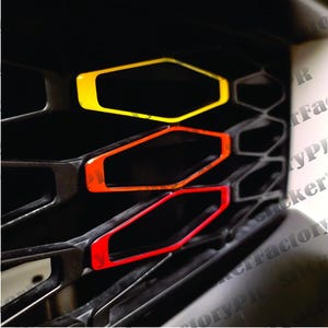 Pu&ograve; includere: Una griglia per auto a nido d'ape nera con tre inserti decorativi disposti in un gradiente verticale. L'inserto superiore &egrave; giallo, quello centrale &egrave; arancione e quello inferiore &egrave; rosso. Ogni inserto &egrave; un telaio esagonale con finitura liscia.