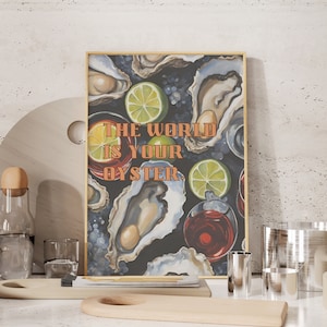 May include: A framed art print with the text "THE WORLD IS YOUR OYSTER" features oysters, lime slices, and red wine glasses on a dark background. The print is displayed on a white surface with wooden serving boards and glassware.