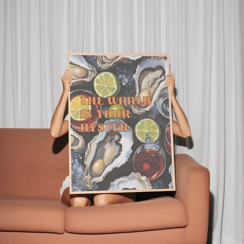 May include: A framed art print featuring an oyster-themed illustration with the text "THE WORLD IS YOUR OYSTER." The artwork includes images of oysters, lime slices, and drinks, set against a dark background. The frame is a light wood color.