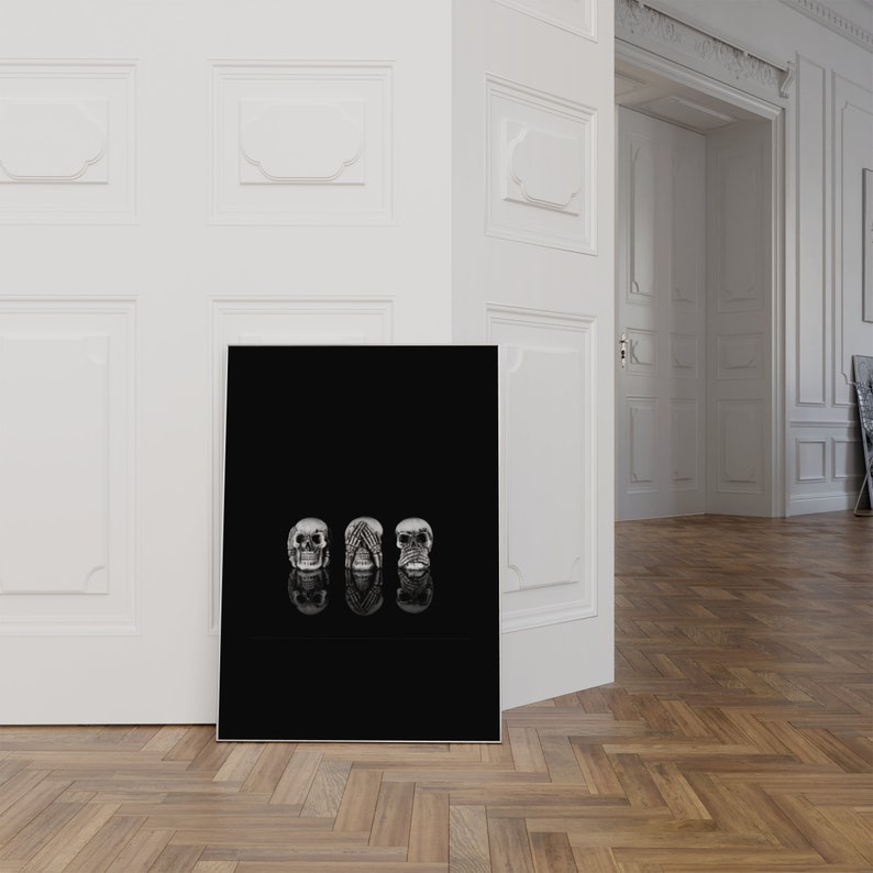 May include: A monochrome art print showing three skull sculptures. Each skull embodies a different concept: see no evil, hear no evil, and speak no evil. The skulls are reflected on a black surface.