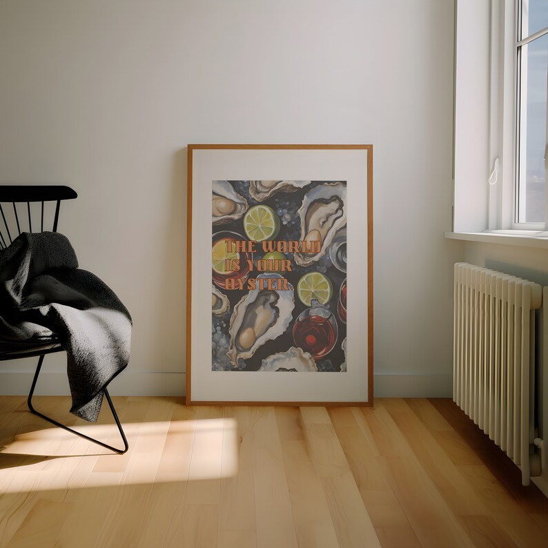 May include: A framed art print featuring an oyster and cocktail illustration. The artwork includes the text "The World Is Your Oyster" in orange and green. The print is displayed in a room with a chair and a window.